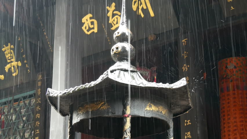 Top of shrine in which offerings to the spirits are burnt with Chinese gold script behind, & rain falling, Qingcheng mountain Chengdu, place of founding of Chinese Taoism