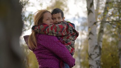 Young boy hugging his mother,outdoors in autumn