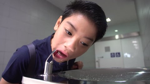  Asian hungry boy drinking water from water tube.