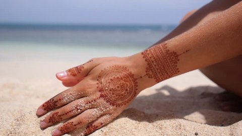 Sand Through Fingers on Beach. Hands with Henna Tattoo