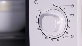 Man using microwave close-up. Closing door of the microwave oven and setting cooking time turning on the timer knob