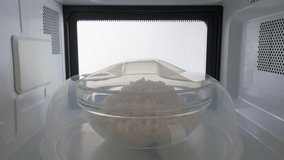 Cooked white rice covered with plastic plate cover heating in the microwave oven