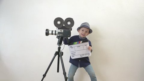 Funny child holding a clapboard, little director having fun, old camera, action