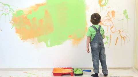 Little child painting the wall, funny boy enjoying to decorate the wall
