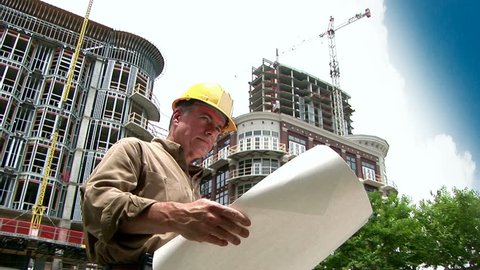 architect looking at building plans, then rolling them up and smiling at the camera.