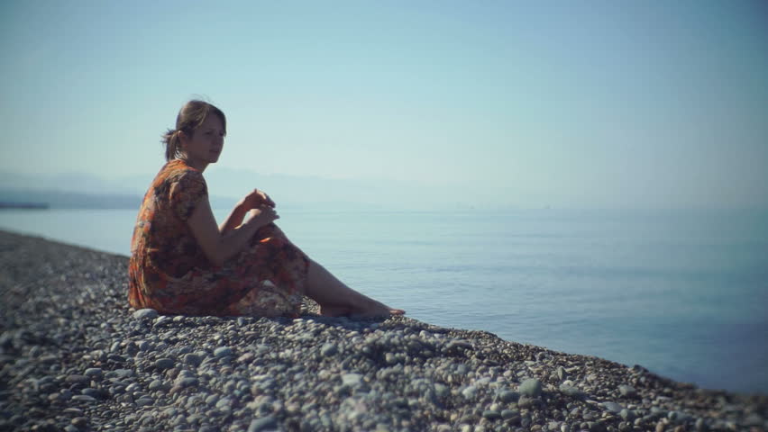 The kid goes to a young mother and hugging her. On the beach, in the sun.
