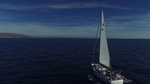 Flying near the sailing yacht in the sea. White cruise sailboat. Flying around sailing vessel in the sea. Aerial view.