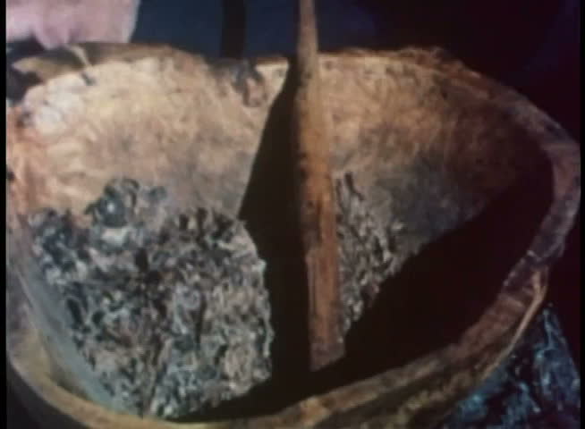 Close-up of hands pouring melted animal fat into bowl with dried meat