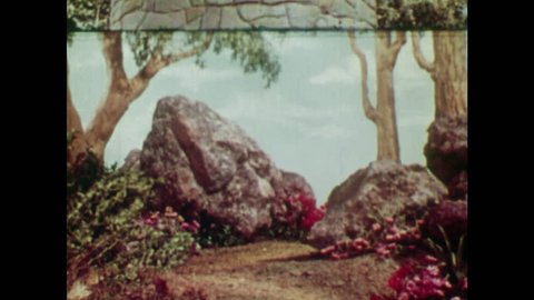 ANIMATED 1950s: Witch walks towards Rapunzel's tower. Young man sees a witch coming so hides behind a rock. Witch calls up to Rapunzel in her tower as young man watches.