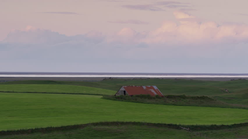 Wide panning shot of house in remote landscape / Kirkjuaejarklaustur, Vestur-Skaftafellssysla, Iceland