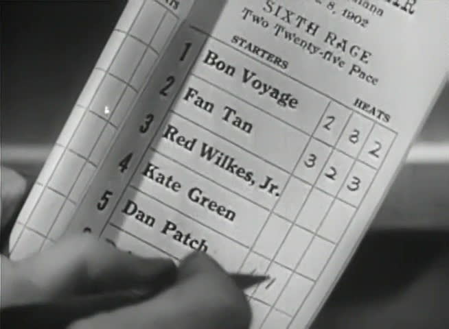 Close-up of hand choosing horses on racing form
