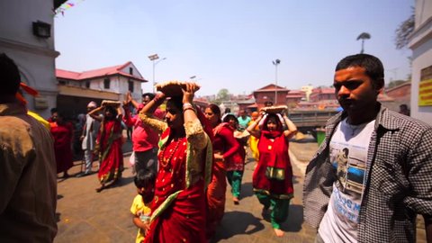 KATHMANDU, NEPAL - APRIL 11, 2016: People carry food and flowers offerings for deity into the main Pashupatinath Temple which non hinduites aren't allowed to visit.