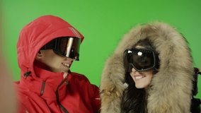 Beautiful couple taking selfie with ski suits on green screen and demonstrating different versions of emotions and poses.  With photo camera flash light. Shot on RED EPIC DRAGON Cinema Camera.