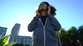 Portrait of mixed race girl in park listening to music on smartphone