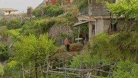 Wide crane shot of man tilling soil on farm / Scala, Campania, Italy