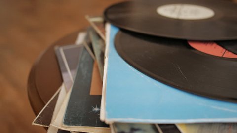 Close up of male hand gently pulls vintage vinyl record out of its cover in the LP collection stack.