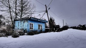 Blue abandoned one-story house trailer. Former lodge - checkpoint. Wires against sky. Autumn. The snow and bare trees without leaves. Enhanced video contrast. November 2016. Russia Omsk