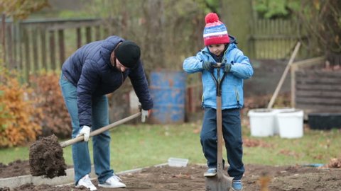 Father and son, working together in garden, autumntime, shoveling the soil for the winter