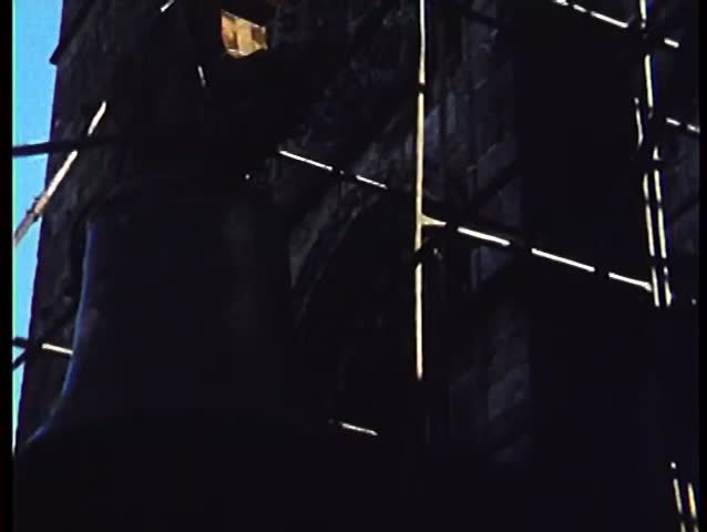 People hoisting bell to top of tower
