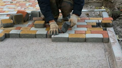 Laying Paving Slabs by mosaic close-up. Road Paving, construction. Repairing sidewalk. Worker laying stone paving slab. Laying colored tiles in a city park. Hand fixed tessellated sidewalk tile