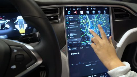 HELSINKI, FINLAND - NOVEMBER 04, 2016: The interior of a Tesla Model X electric car with large touch screen dashboard. Woman tasting a new vehicle functions. DIGIEXPO 2016 in Messukeskus Expocenter.