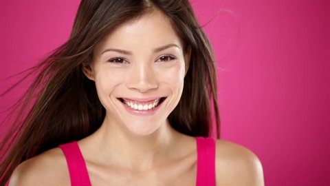 Beautiful smiling woman closeup portrait. Fresh gorgeous young mixed race Caucasian / Asian Chinese woman looking cheerful at camera on pink background. Stock-video
