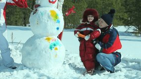 Happy family of four painting the snowman made not far from winter forest
