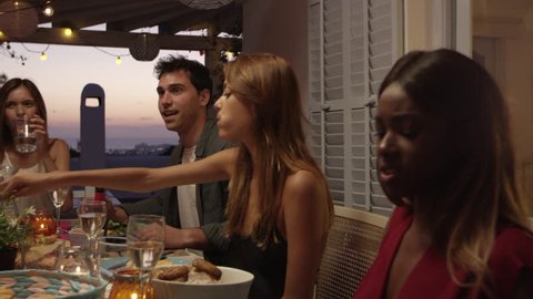 Friends talking at a dinner party on a roof terrace, Ibiza, shot on R3D