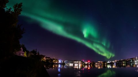 Aurora borealis over Reykjavik pond city lights water reflection realistic 4k
