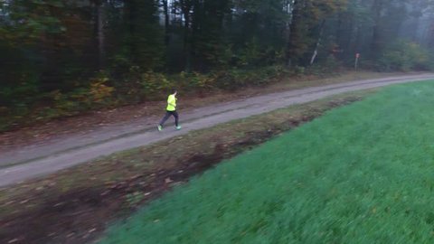 Jogger running in the forest with mist and fog and the drone is following him amazing autumn shot video 4K aerial drone footage.