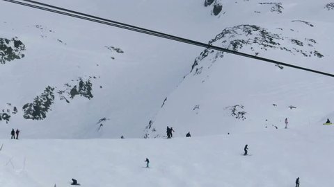 Skiers who are preparing to descend on a snowy slope while a cable car passes by her 38
