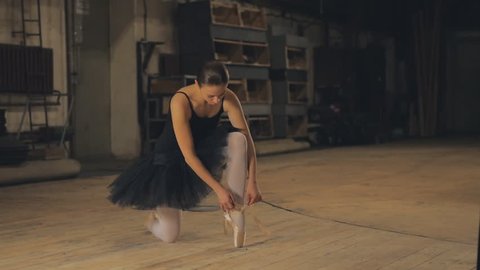 Ballerina tying pointe shoes backstage
