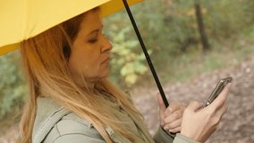 Outdoor using of wireless Internet connection of blond woman slow motion 1920X1080 HD footage - Blonde female with yellow umbrella in forest slow-mo 1080p FullHD video