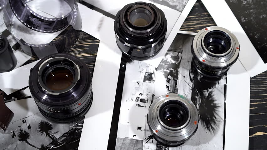 Vintage 35mm cameras, lenses, photos and film are piled up.
