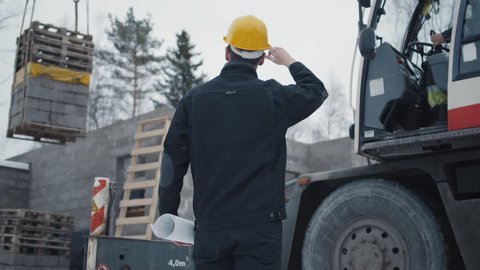 Construction Worker Signals to Crane Operator on Construction Site. Shot on RED Cinema Camera in 4K (UHD).
