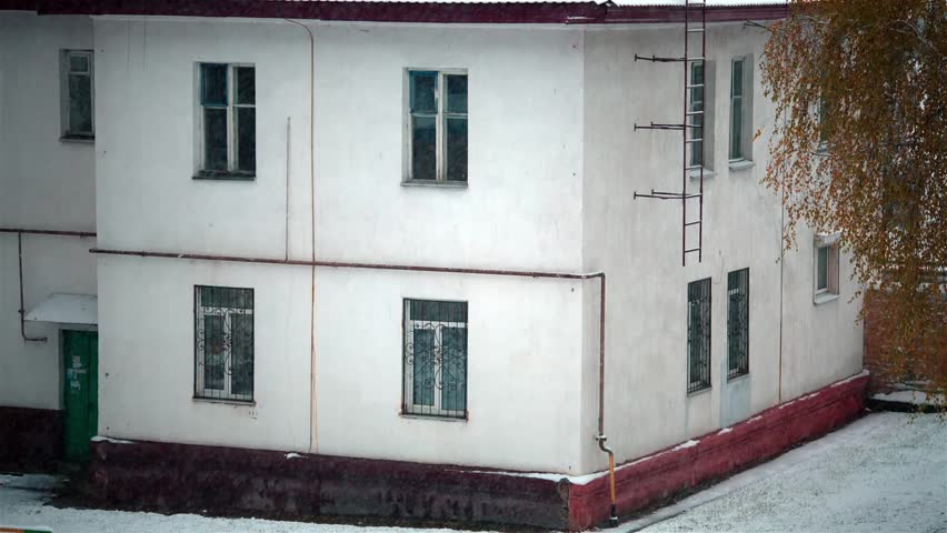 Snowflakes smoothly fall opposite to a facade of the ancient building.