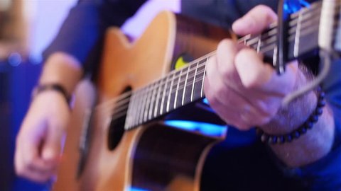 Playing guitar hands close up acoustic with pick slow motion shallow depth of field. Teenager musician press chords and fingers touch strings with plectrum. Rock star performs solo rehearsal concert 