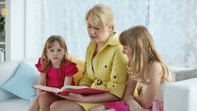 Mother reading a fairy-tail to her daughters, a little girl and a teenager