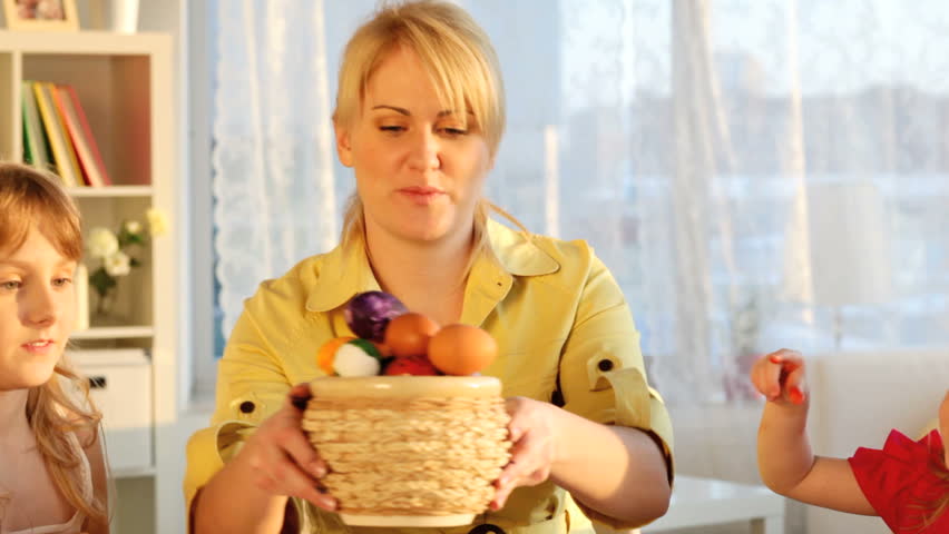 Mom and daughters celebrating Easter by following a famous tradition of knocking eggs together