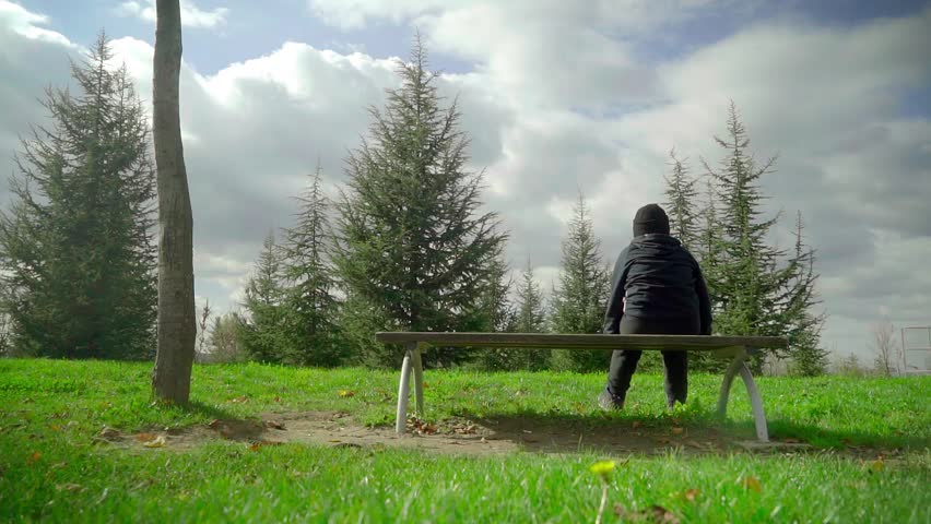On a sunny autumn day in the park, a little boy sits on a bench wondering what to do.