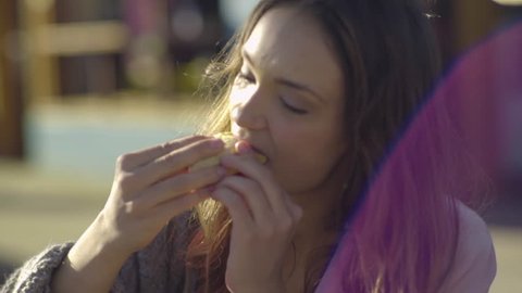 Closeup Of Young Woman Eating A Taco, Her Friend Talks On The Phone Next To Her