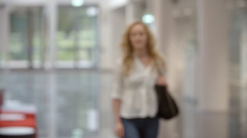 Blonde female university student walking into focus in lobby
