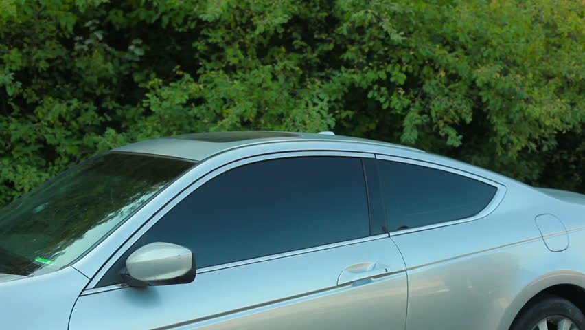 Young man approaching and entering grey car