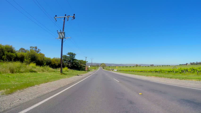 MCLAREN VALE, SOUTH AUSTRALIA - NOVEMBER 5, 2016: Automobile POV driving along Main Road, McLaren Vale, South Australian winery region, past wineries with views  of grapevines, fast motion. 
