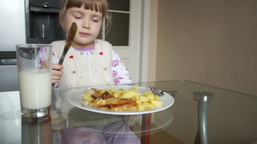 Little girl eating a potato with a knife