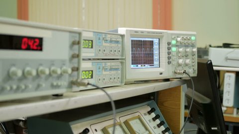 Equipment for measuring electrical signals is in the physical laboratory. The scoreboard lit instrumentation data. Oscilloscope and a pulse generator working together.