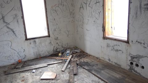 4K Corner of room in forsaken house with empty window frames, garbage around
