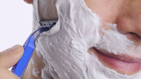 Man shaving with foam and manual razer. Close up of man shaving beard.