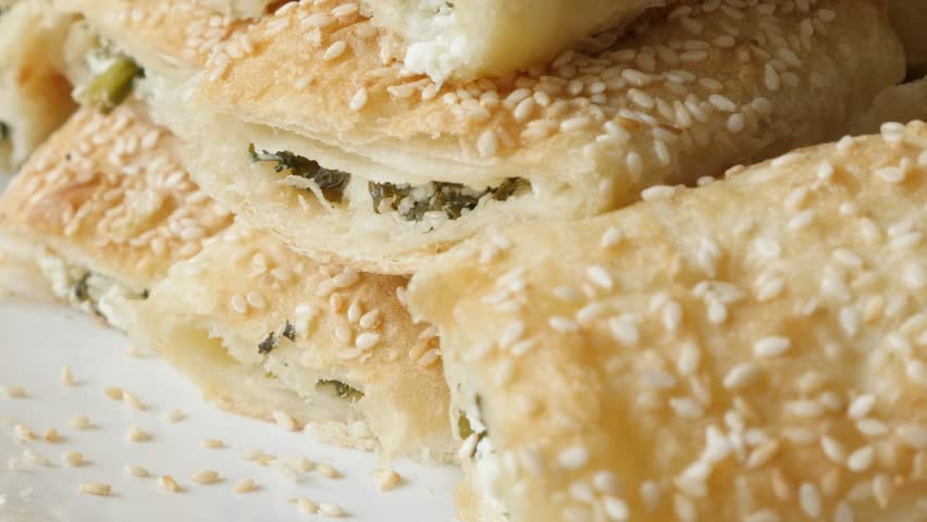 Served on plate filo pie with sesame cheese and spinach slow tilt 4K 2160p 30fps UHD footage - Thin sheets of dough rolls baked with filling close-up 3840X2160 UltraHD  tilting video
