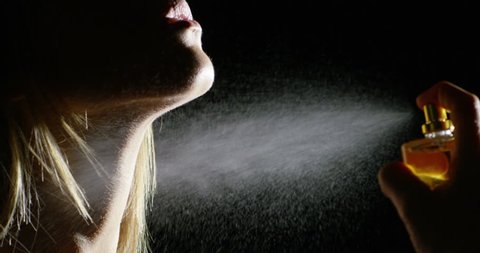 Anonymous sensual girl spraying fragrance in extreme slow motion, with scent particles to wet skin after showering.
concept of sensual feminine scent Women / Lady